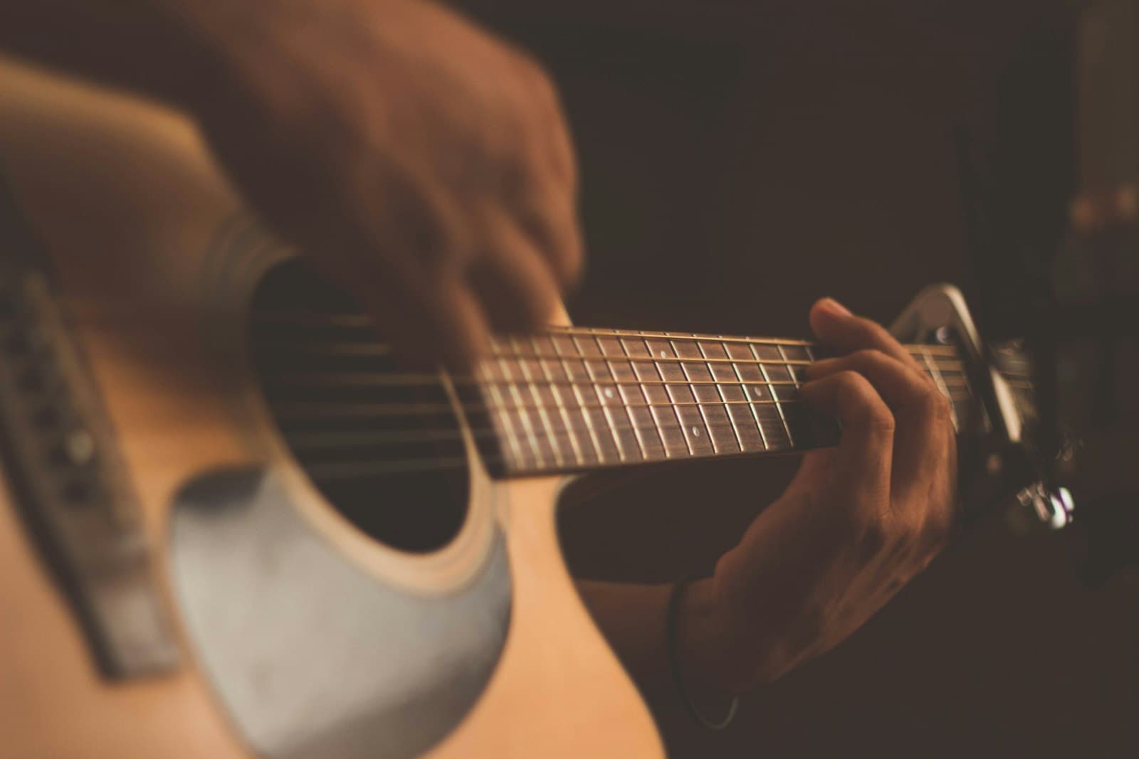 Manos tocando fingerstyle en una guitarra acústica
