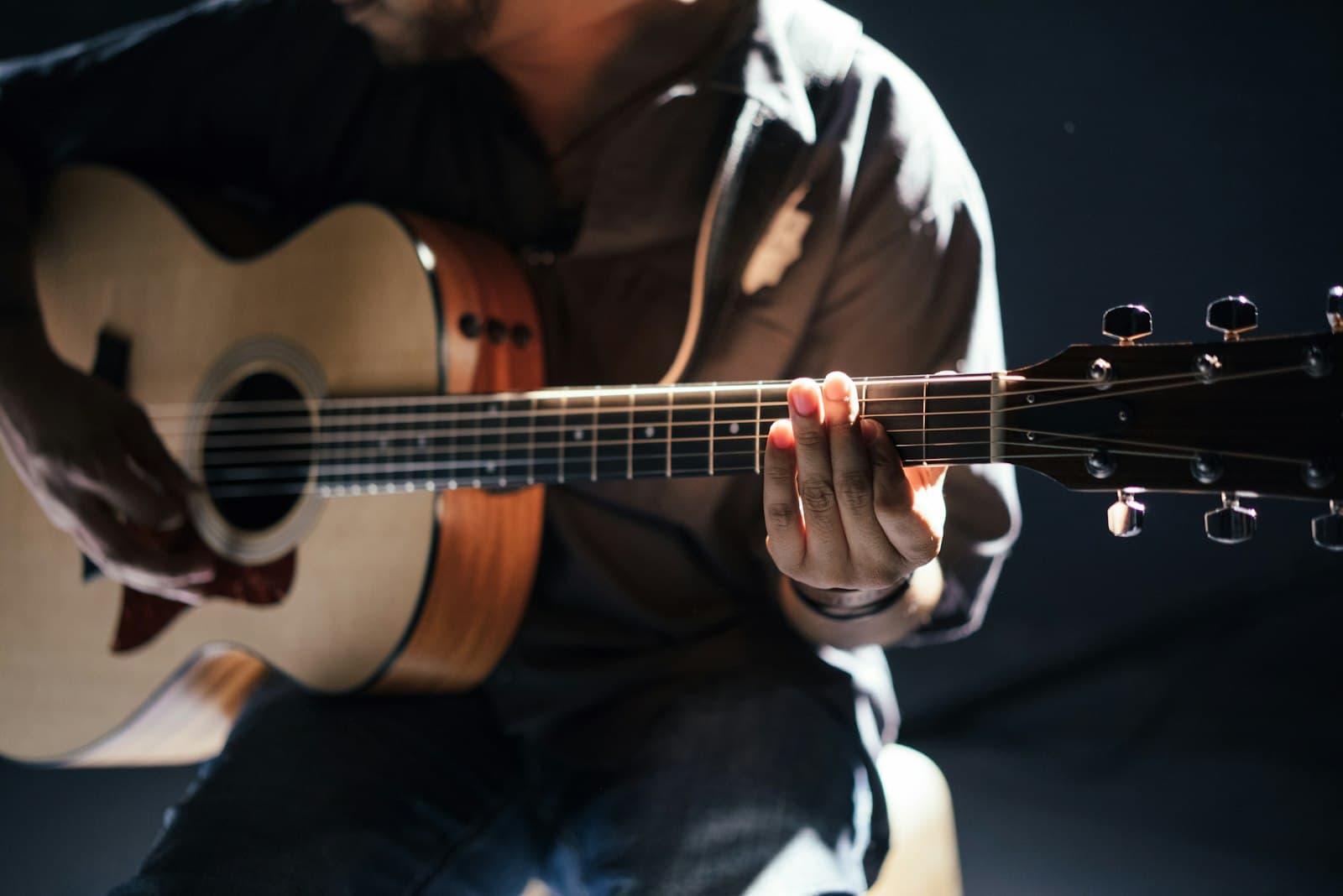 Guitarrista tocando fingerstyle bajo la luz del estudio